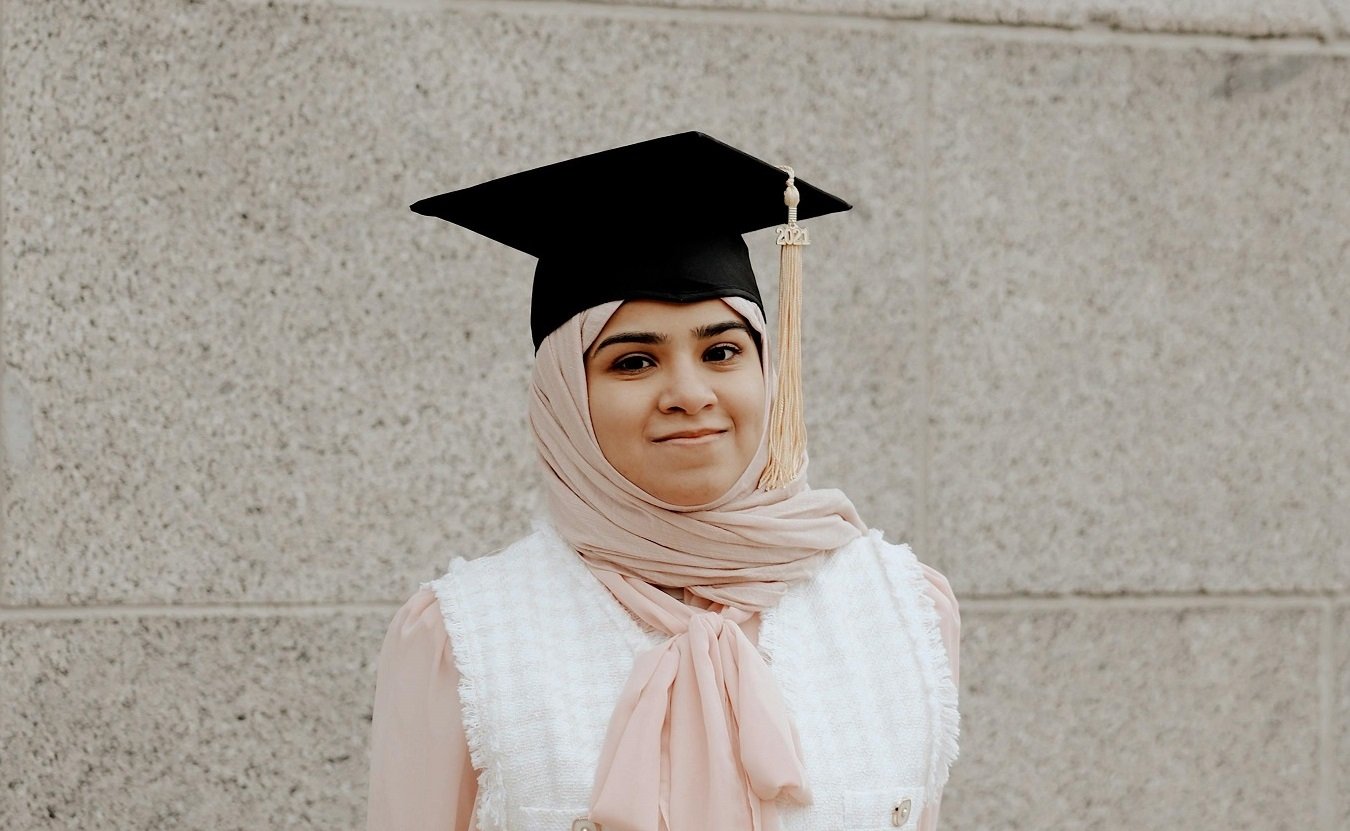 A women in a traditional university graduation cap, looking proud