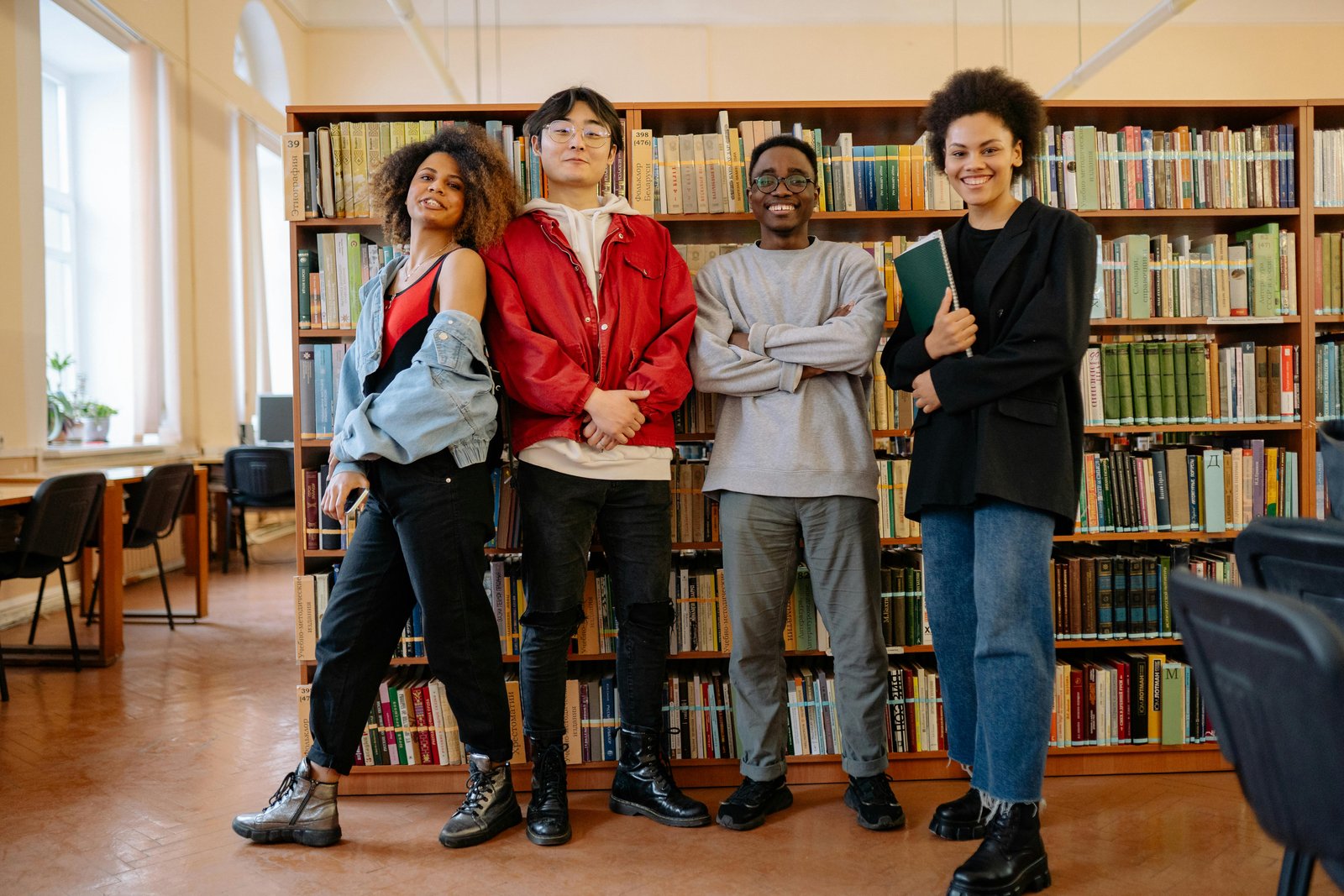Group of students standing together, smiling, with the backgroup of a library