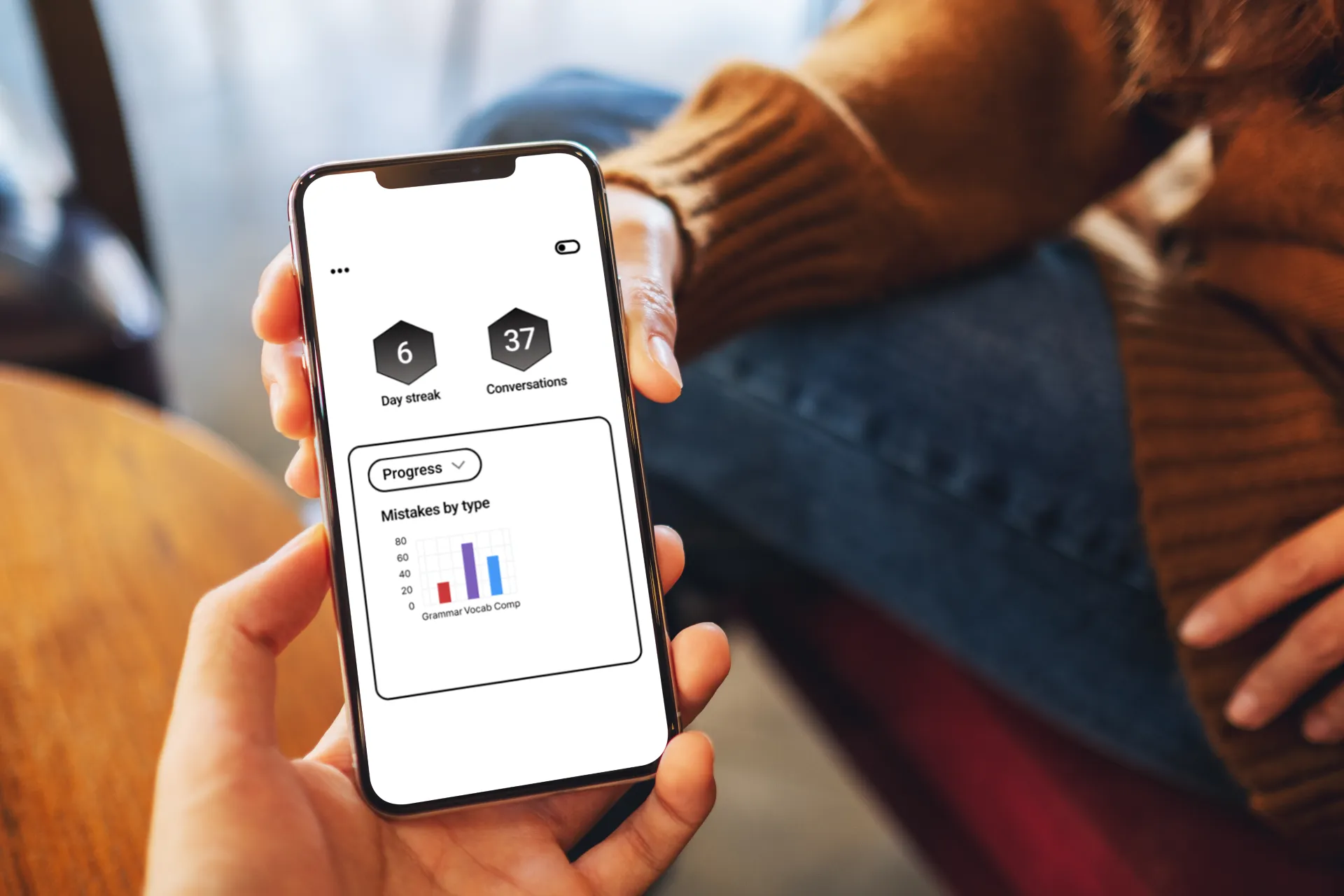 A student passing their teacher a smartphone. The screen displays a report provided by the Versa practice application, which highlights mistakes the student has made in their written English.